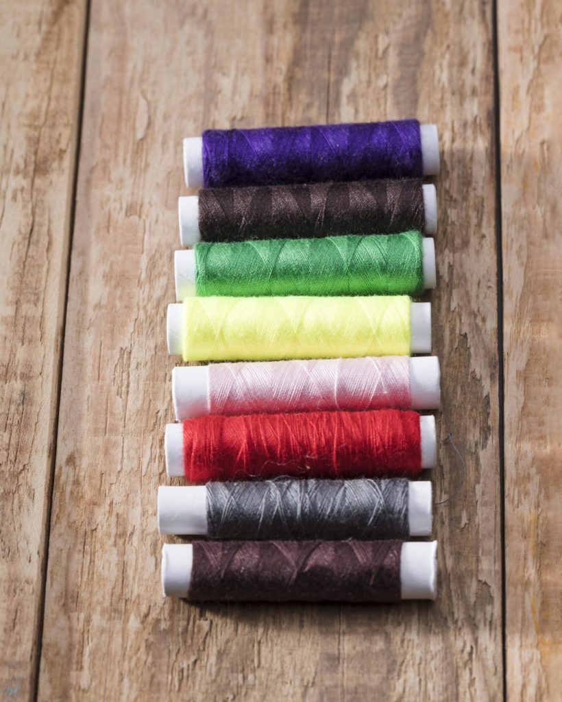 high-angle-multicolored-thread-reels-wooden-surface